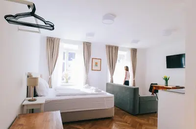 a bedroom with a bed and a woman standing in a window at Central Riverside Apartments Meščanka in Ljubljana