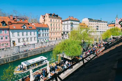 a crowd of people walking along a river with a bus at Central Riverside Apartments Meščanka in Ljubljana