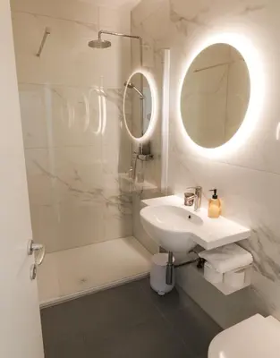 a white bathroom with a sink and a shower at Central Riverside Apartments Meščanka in Ljubljana
