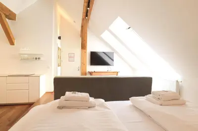 a white bedroom with a bed and a tv at Central Riverside Apartments Meščanka in Ljubljana