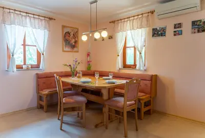 a dining room with a wooden table and chairs at PLANINCA -hiša z razgledom in Šmarje pri Jelšah