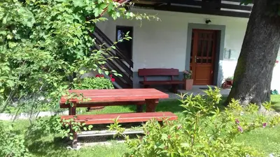 a red bench sitting in front of a house at Apartma Pr Gatej in Bohinj
