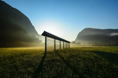 a smallshed in a field with mountains in the background at Apartma Pr Gatej in Bohinj
