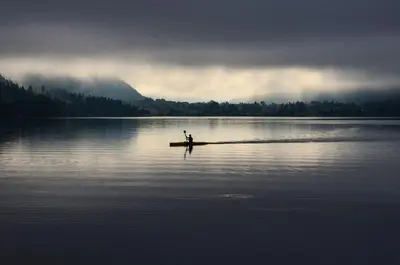 a person is sitting on a boat in the water at Apartma Pr Gatej in Bohinj