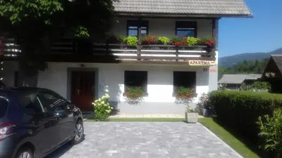 a car parked in front of a white house at Apartma Pr Gatej in Bohinj