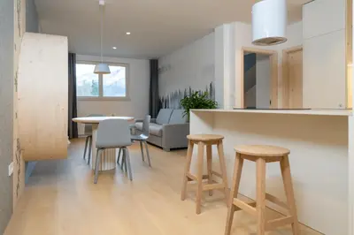 a kitchen and living room with a table and stools at TD Bohinj Apartments in Bohinj