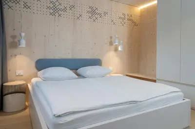 a bedroom with a white bed with a blue headboard at TD Bohinj Apartments in Bohinj
