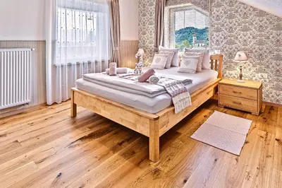 a bedroom with a large bed with wooden floors and a window at Apartments Koledniki in Bled