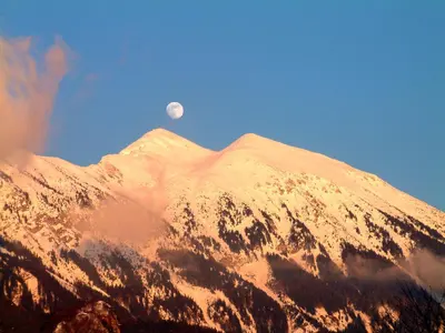 a snow covered mountain with the moon in the sky at Apartment Pod Skalco in Jesenice
