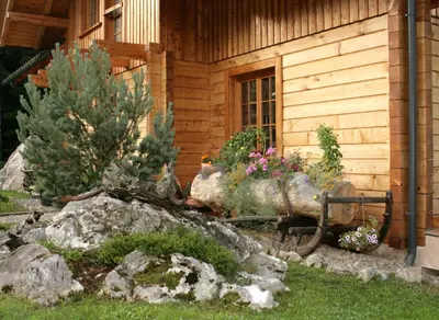 a log cabin with flowers in front of a building at Apartment Pod Skalco in Jesenice