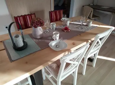 a wooden table with white chairs and a table cloth at Hillside Bio Resort Delux Apartments in Šešče pri Preboldu