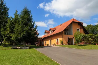 a yellow house with a red roof on a road at Wine House Kaloh in Maribor