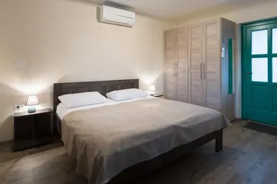 a bedroom with a large bed with two tables and a green door at Guest House Valentincic in Nova Gorica