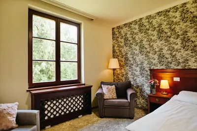 a bedroom with a bed and a chair and a window at Mokrice Castle Estate in Čatež ob Savi