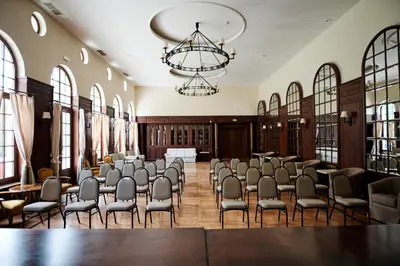 a room with rows of chairs and a chandelier at Mokrice Castle Estate in Čatež ob Savi