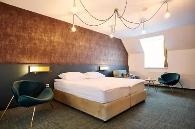 a hotel room with a bed and two chairs at Mokrice Castle Estate in Čatež ob Savi
