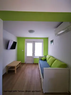 a room with green walls and a bed and a table at Apartment and room Anica in Tolmin