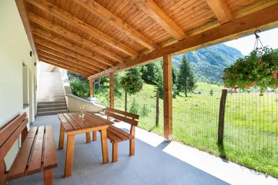 a wooden patio with a table and benches on a porch at House DorMica in Trenta