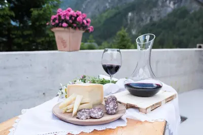 a table with a plate of cheese and a glass of wine at House DorMica in Trenta