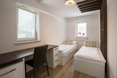 a small room with a desk and a bed and window at Apartments Vila Apolonia in Ljubljana