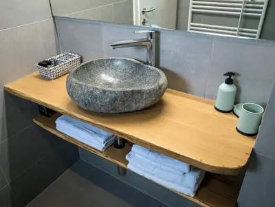 a bathroom sink on a wooden shelf with towels at Apartments Vila Apolonia in Ljubljana