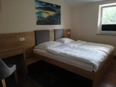 a bedroom with a large bed with a desk and a window at GOSTILNA S PRENOČIŠČI PAV in Rakek