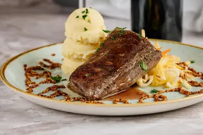 a plate of food with a piece of meat and ice cream at GLUTEN FREE Bed & Breakfast Dežela Okusov in Ljubljana