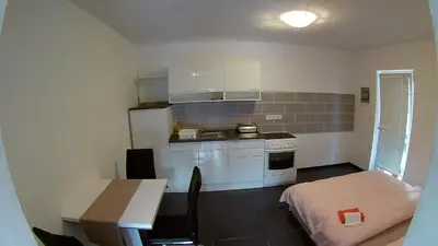 a small kitchen with white cabinets and a table at Apartma Jernej in Bovec