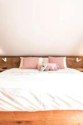 a bed with white sheets and pink pillows at Terasse Jeruzalem Apartments in Hermanci