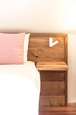 a bed with a wooden headboard with a white pillow at Terasse Jeruzalem Apartments in Hermanci