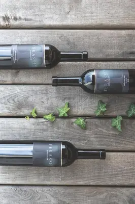 three bottles of wine sitting on a wooden table at Terasse Jeruzalem Apartments in Hermanci