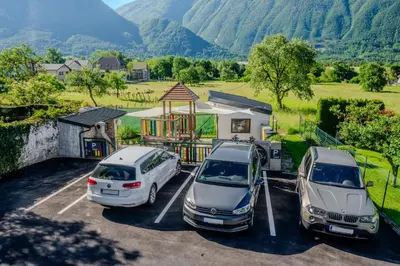 two cars parked in a parking lot with mountains in the background at Penzion Hosnar, apartma Time Out in Bovec