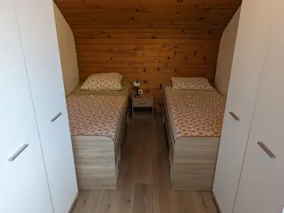 two beds in a small room with wooden walls at Apartment Bee near Bled in Zabreznica