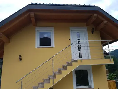 a yellow house with stairs on the side of it at Apartmaji Zupan in Bohinjska Bela