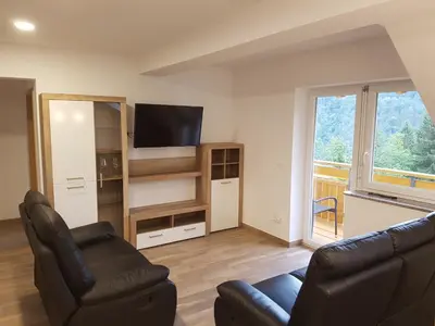 a living room with two chairs and a television at Apartmaji Zupan in Bohinjska Bela