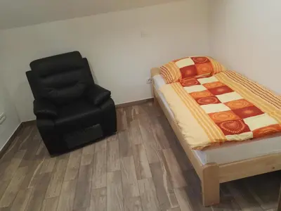a bedroom with a bed and a black chair at Apartmaji Zupan in Bohinjska Bela
