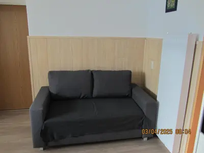 a black couch in a room with a wall at Apartma Vilma in Kobarid