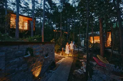 a couple walking down a path in a forest at Theodosius Forest Village - Glamping in Vipava valley in Vipava