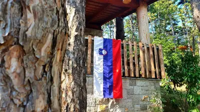 a flag is hanging on a wooden fence at Theodosius Forest Village - Glamping in Vipava valley in Vipava