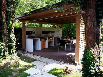 a patio with a kitchen and a table under a canopy at River house HRIB in Preddvor