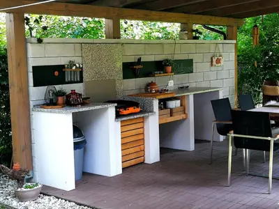 an outdoor kitchen with a table and chairs on a patio at River house HRIB in Preddvor