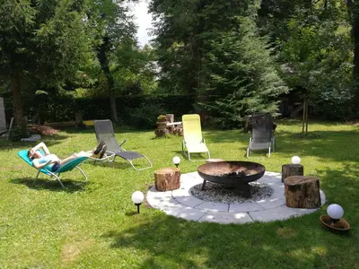 a woman laying in a chair next to a fire pit at River house HRIB in Preddvor