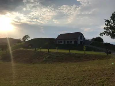 a house on top of a hill with the sun setting at Tourist farm Artisek in Štore
