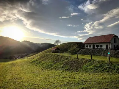 a house on top of a hill with the sun in the sky at Tourist farm Artisek in Štore