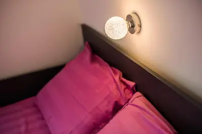 a bed with a pink pillow and a light on the wall at Golf apartment with SPA tickets discount in Moravske Toplice
