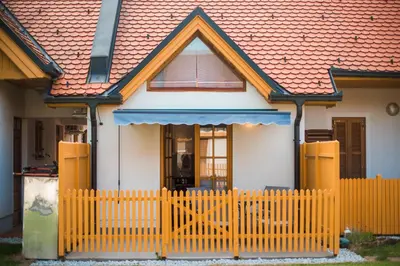 a house with a yellow fence in front of it at Golf apartment with SPA tickets discount in Moravske Toplice