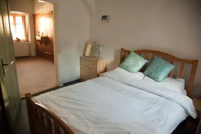 a bedroom with a bed with white sheets and blue pillows at The 1882 Old House Vodnikova in Bohinj