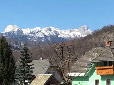 a group of houses with snow capped mountains in the background at The 1882 Old House Vodnikova in Bohinj