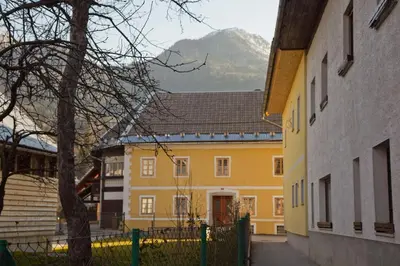 a yellow building with a mountain in the background at The 1882 Old House Vodnikova in Bohinj