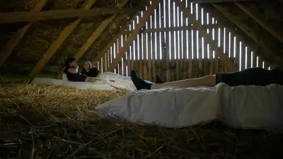 two women laying on beds in a barn with hay at Hrgova hiška in Ptuj